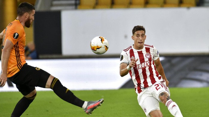 Olympiakos Kostas Tsimikas, right, kicks the ball during the Europa League round of 16 second leg soccer match between Wolves and Olympiakos at Molineux Stadium in Wolverhampton, England, Thursday, Aug. 6, 2020. (AP Photo/Rui Vieira)