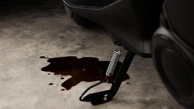 Oil leak or drop from engine of motorcycle on concrete floor , check and maintenance