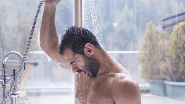 The man is taking a shower in the hot water with a view of the forest