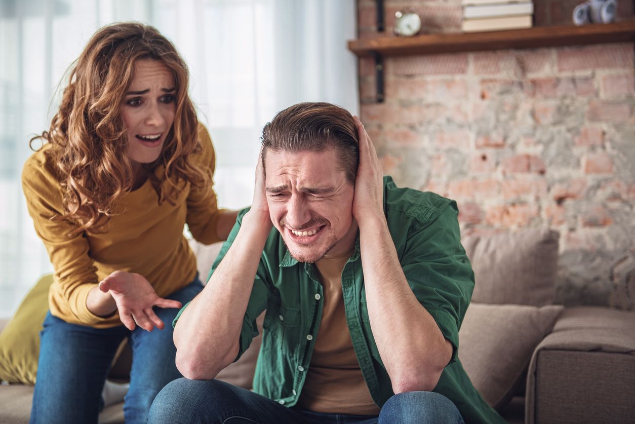 Listen to me. Angry man is closing his ears with desperation while his wife is shouting at him. Family conflict concept
