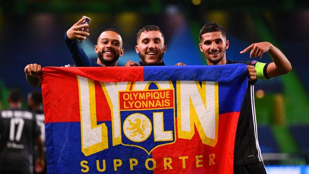LISBON, PORTUGAL - AUGUST 15: Memphis Depay, Rayan Cherki and Houssem Aouar of Olympique Lyon celebrate with a supporters flag following their team's victory in the UEFA Champions League Quarter Final match between Manchester City and Lyon at Estadio Jose Alvalade on August 15, 2020 in Lisbon, Portugal. (Photo by Franck Fife/Pool via Getty Images)
