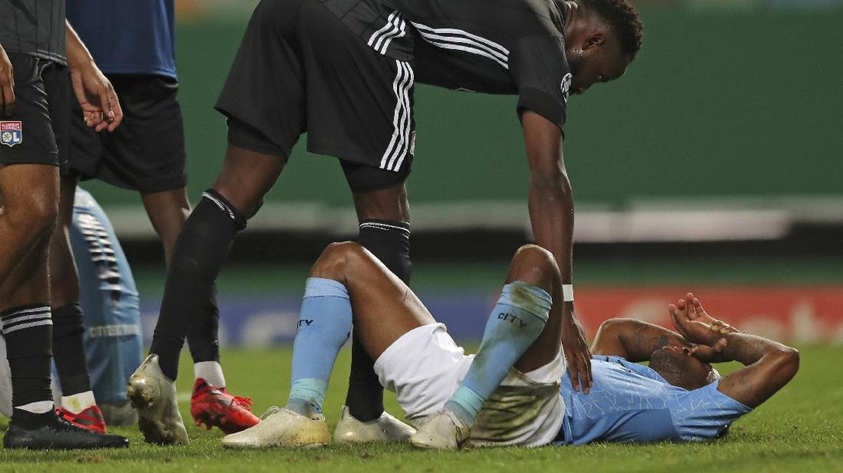 Raheem Sterling ditenangkan pemain Lyon, usai Manchester City kalah 1-3 di perempatfinal Liga Champions. (Foto: Miguel A. Lopes/Pool via AP)