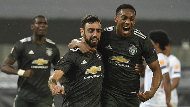 Manchester United's Bruno Fernandes, left celebrates after scoring the opening goal of the game during the Europa League semifinal soccer match between Sevilla and Manchester United in Cologne, Germany, Sunday, Aug. 16, 2020. (Ina Fassbender/Pool Via AP)