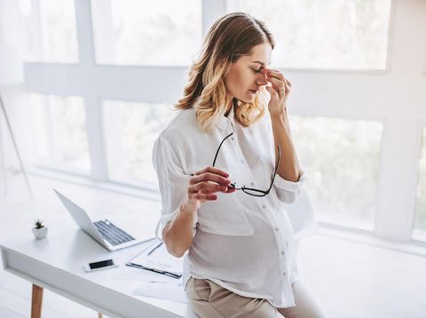 Above high angle view of nice lovely beautiful minded serious pregnant curly-haired mom in casual wear sitting on sofa, couch, divan, working remotely, lotus pose, white light interior room