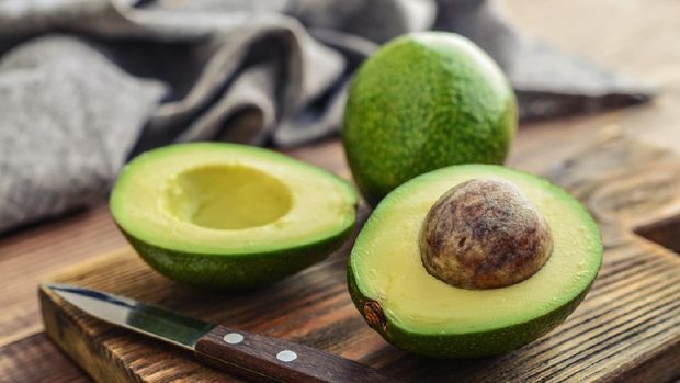 Avocado on old wooden table in bowl. Halfs of avocados fresh fruits healthy food.