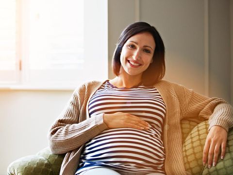 Portrait of a smiling pregnant woman sitting on her sofa