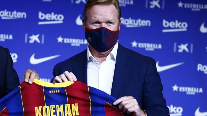 Ronald Koeman holds up a soccer shirt with his name on it during his official presentation as coach for FC Barcelona in Barcelona, Spain, Wednesday, Aug. 19, 2020. Barcelona officially announced earlier on Wednesday a deal with Koeman to become their coach five days after the teams humiliating 8-2 loss to Bayern Munich in the Champions League quarterfinals. Barcelona says the former defenders deal runs through June 2022. Koeman replaces the fired Quique Setien. (AP Photo/Joan Monfort)