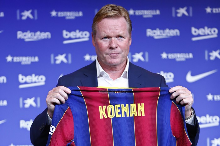 Ronald Koeman holds up a soccer shirt with his name on it during his official presentation as coach for FC Barcelona in Barcelona, Spain, Wednesday, Aug. 19, 2020. Barcelona officially announced earlier on Wednesday a deal with Koeman to become their coach five days after the teams humiliating 8-2 loss to Bayern Munich in the Champions League quarterfinals. Barcelona says the former defenders deal runs through June 2022. Koeman replaces the fired Quique Setien. (AP Photo/Joan Monfort)