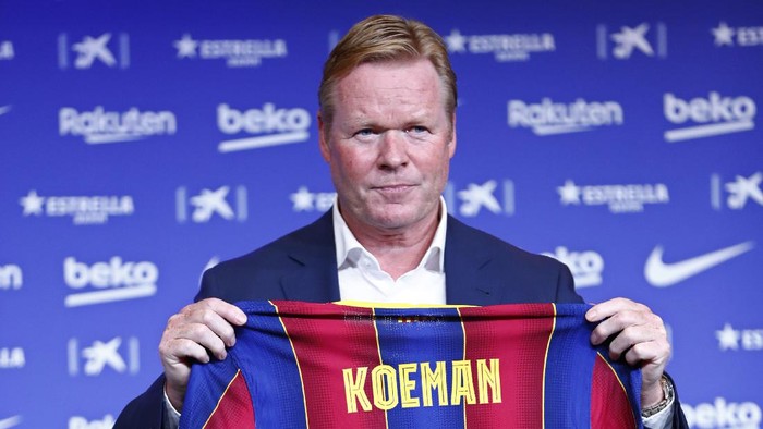 Ronald Koeman holds up a soccer shirt with his name on it during his official presentation as coach for FC Barcelona in Barcelona, Spain, Wednesday, Aug. 19, 2020. Barcelona officially announced earlier on Wednesday a deal with Koeman to become their coach five days after the teams humiliating 8-2 loss to Bayern Munich in the Champions League quarterfinals. Barcelona says the former defenders deal runs through June 2022. Koeman replaces the fired Quique Setien. (AP Photo/Joan Monfort)