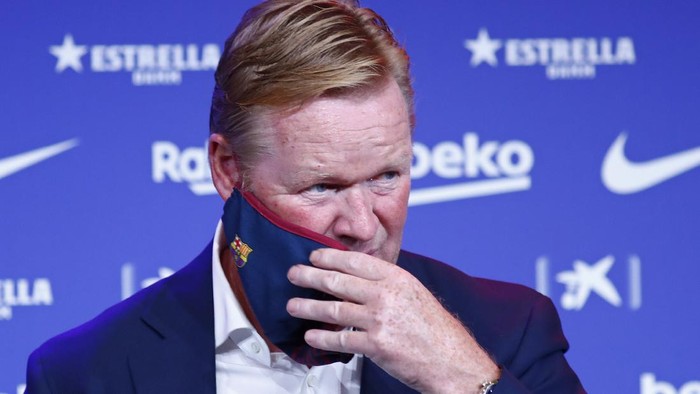 Ronald Koeman takes of his protective face mask during his official presentation as coach for FC Barcelona in Barcelona, Spain, Wednesday, Aug. 19, 2020. Barcelona officially announced earlier on Wednesday a deal with Koeman to become their coach five days after the teams humiliating 8-2 loss to Bayern Munich in the Champions League quarterfinals. Barcelona says the former defenders deal runs through June 2022. Koeman replaces the fired Quique Setien. (AP Photo/Joan Monfort)