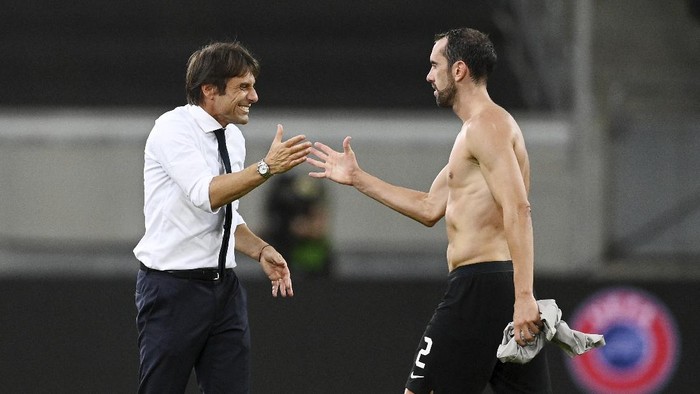 Inter Milans head coach Antonio Conte, left, smiles with his player Diego Godin during the Europa League semifinal soccer match between Inter Milan and Shakhtar Donetsk at Dusseldorf Arena, in Duesseldorf, Germany, Monday, Aug. 17, 2020. (Sascha Steinbach, Pool Photo via AP)