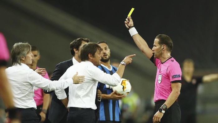 Referee Danny Makkelie gives a yellow card to Inter Milans head coach Antonio Conte during the Europa League final soccer match between Sevilla and Inter Milan in Cologne, Germany, Friday, Aug. 21, 2020. (Lars Baron, Pool Photo via AP)