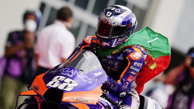 Portugal's KTM driver Miguel Oliveira carries a flag after winning the MotoGP race at the Austrian motorcycle Grand Prix at the Red Bull Ring in Spielberg, Austria, Sunday, Aug. 23, 2020. (AP Photo/Steve Wobser)