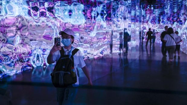 A woman uses her mobile phone to take a picture as she visits a light immersive experience exhibition during the 2020 Beijing International Light Festival at a park in Beijing on August 22, 2020. (Photo by WANG ZHAO / AFP)