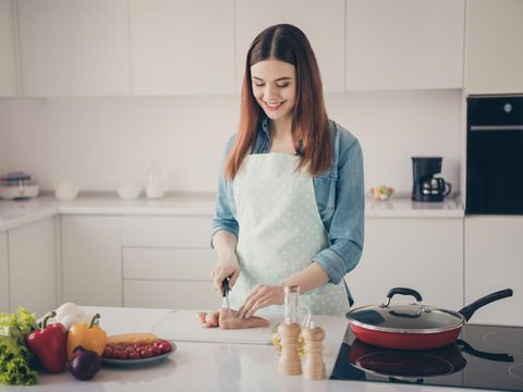 Photo of attractive house, wife making perfect supper for family cut hen meat for new recipe dish