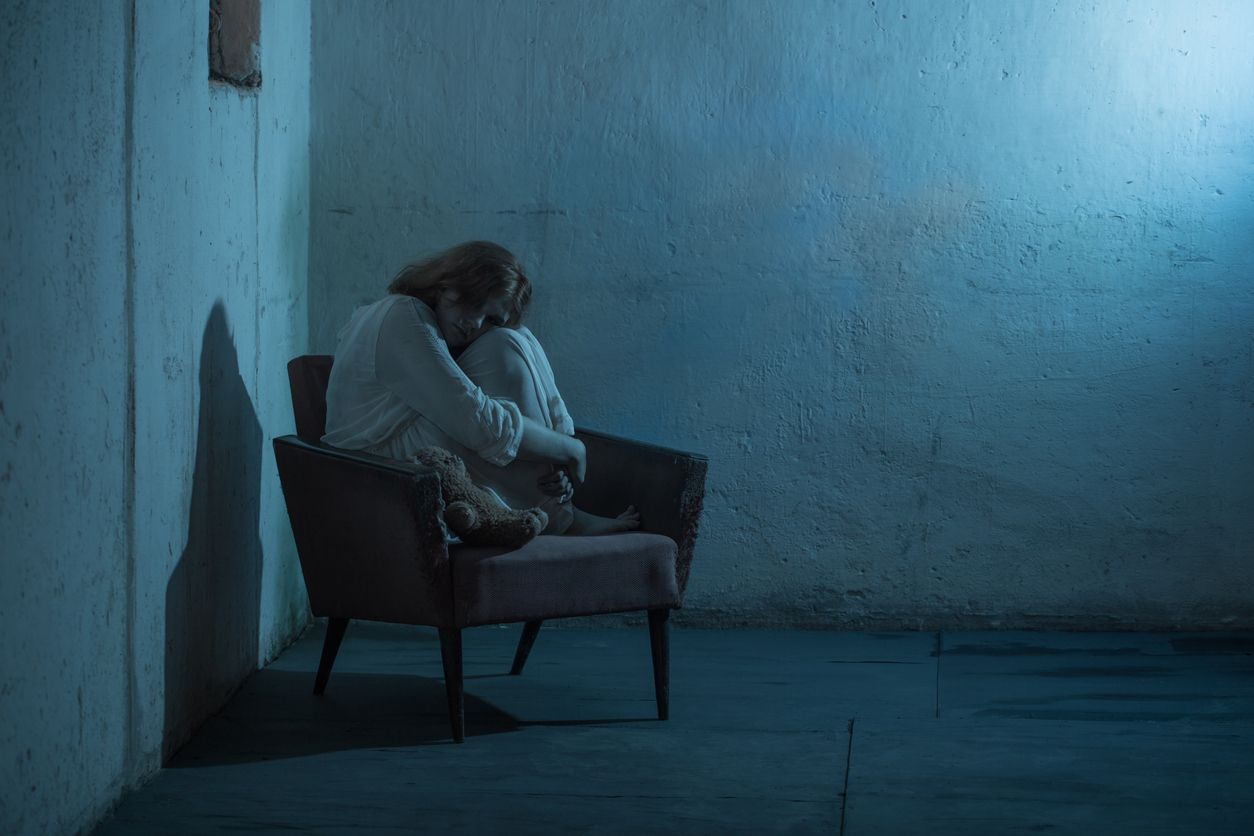 girl in white dress on old armchair  in basement