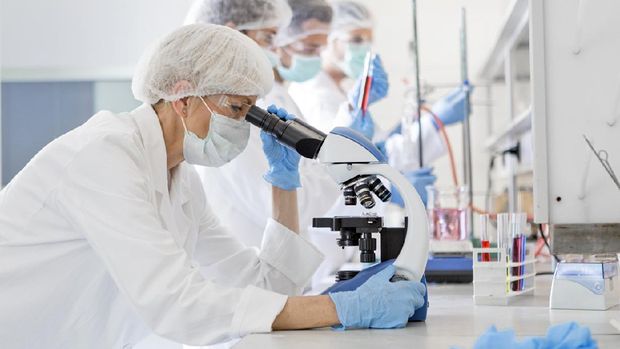 Scientists in protective suits in a science laboratory study a virus