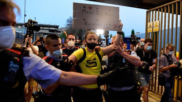 An FC Barcelona fan is escorted out of the Camp Nou stadium premises in Barcelona on August 26, 2020 as fans gather after Barcelona's Argentinian forward Lionel Messi announced his desire to leave the club. - Lionel Messi's bombshell request to leave Barcelona is expected to spark a legal battle over a multi-million-dollar buy-out clause but also raises the question of which club could afford him in the heat of the coronavirus pandemic. (Photo by Pau BARRENA / AFP)