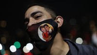 Seorang fan memakai masker bergambar Leonel Messi dan Diego Maradona.