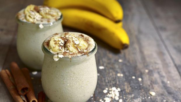Banana smoothie with oats in a vintage glass jar on a rustic wooden table.