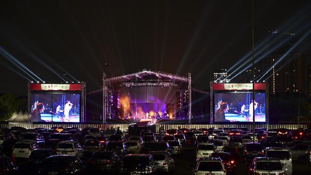 Gemerlap Konser Musik Drive in Pertama di Jakarta People watch Indonesian band 'Kahitna' from their cars during a drive-in live music concert in Jakarta on August 29, 2020, amid the Covid-19 coronavirus pandemic. (Photo by ADEK BERRY / AFP)