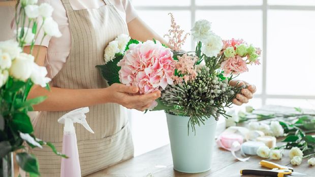 Young female florist working with flowers making bouquet