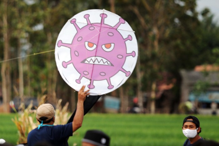 Warga menerbangkan layang-layang bergambar virus Corona di Desa Ngaran, Margokaton, Seyegan, Sleman, Yogyakarta, Rabu (2/8/2020). Layang-layang bertemakan Corona tersebut menjadi media edukasi bagi masyarakat tentang bahaya virus Corona dan ajakan untuk selalu melakukan gerakan 3M yakni dengan Menggunakan Masker, Mencuci Tangan dan Menjaga Jarak.