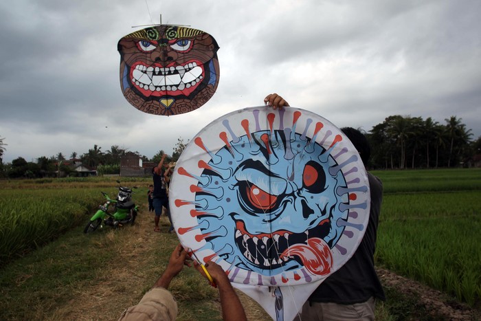 Warga menerbangkan layang-layang bergambar virus Corona di Desa Ngaran, Margokaton, Seyegan, Sleman, Yogyakarta, Rabu (2/8/2020). Layang-layang bertemakan Corona tersebut menjadi media edukasi bagi masyarakat tentang bahaya virus Corona dan ajakan untuk selalu melakukan gerakan 3M yakni dengan Menggunakan Masker, Mencuci Tangan dan Menjaga Jarak.