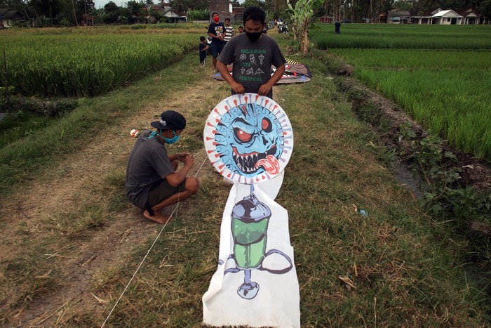 Warga menerbangkan layang-layang bergambar virus Corona di Desa Ngaran, Margokaton, Seyegan, Sleman, Yogyakarta, Rabu (2/8/2020). Layang-layang bertemakan Corona tersebut menjadi media edukasi bagi masyarakat tentang bahaya virus Corona dan ajakan untuk selalu melakukan gerakan 3M yakni dengan Menggunakan Masker, Mencuci Tangan dan Menjaga Jarak.