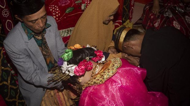 This picture taken on July 25, 2020 shows 18-year-old Lia (C) and her 21-year-old husband Randi (R, not their real names) asking for their parents' blessing after getting married in the village of Tampapadang in Mamuju, West Sulawesi. - Child marriage has long been common in traditional communities from the Indonesian archipelago to India, Pakistan and Vietnam, but numbers had been decreasing as charities made inroads by encouraging access to education and women's health services. (Photo by YUSUF WAHIL / AFP) / TO GO WITH Indonesia-India-Vietnam-children-health-virus-family,FEATURE by Haeril Halim, Aishwarya Kumar and Tran Thi Minh Ha