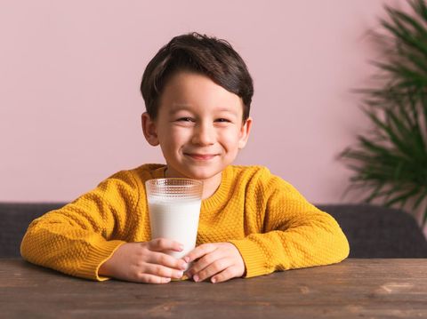 Child drinking a glass of milk. He loves milk. He knows that he needs to drink milk for healthy bones.