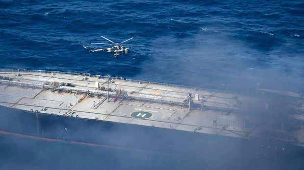 In this photo provided by Sri Lanka Air Force, a chopper flies through smoke rising from the MT New Diamond, off the eastern coast of Sri Lanka in the Indian Ocean,, Saturday, Sept. 5, 2020. The fire on the large oil tanker off Sri Lanka's coast has been brought under control but is still not extinguished, the navy said Saturday. The tanker, carrying nearly 2 million barrels of crude oil, was drifting about 20 nautical miles (37 kilometers) from Sri Lanka's eastern coast and on Friday evening a tug boat towed it to the deep sea away from land, said navy spokesman Capt. Indika de Silva.  (Sri Lanka Air Force via AP)