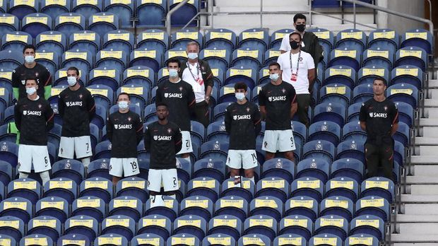 Portugal's Cristiano Ronaldo, right, stands next to the team substitutes on the stands during the UEFA Nations League soccer match between Portugal and Croatia at the Dragao stadium in Porto, Portugal, Saturday, Sept. 5, 2020. Ronaldo is not playing due to an injury. (AP Photo/Miguel Angelo Pereira)