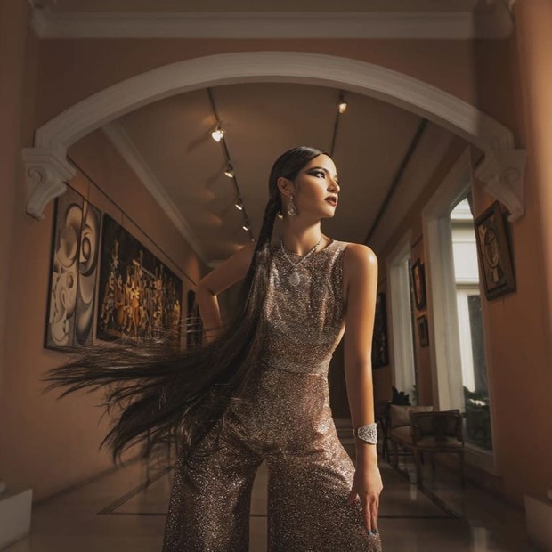 Dalam pemotretan bersama fotografer Rio Motret, Nia Ramadhani mengenakan jumpsuit dengan bahan glittery berwarna cokelat keemasan dari desainer Ivan Gunawan.