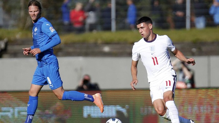 Englands Phil Foden, right, runs with the ball during the UEFA Nations League soccer match between Iceland and England in Reykjavik, Iceland, Saturday, Sept. 5, 2020. England players Phil Foden and Mason Greenwood have been dropped for Tuesdays game against Denmark after breaching coronavirus rules in Iceland. They will return to England from Reykjavik rather than traveling to Copenhagen on Monday Sept. 7, 2020, after social media video was published in Iceland purporting to show the players meeting women from outside the team bubble. (AP Photo/Brynjar Gunnarson)