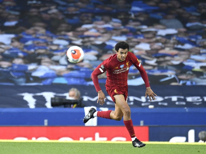LIVERPOOL, ENGLAND - JUNE 21: Trent Alexander-Arnold of Liverpool runs with the ball in front of a banner with photographs of fans displayed in the empty stands during the Premier League match between Everton FC and Liverpool FC at Goodison Park on June 21, 2020 in Liverpool, England. Football Stadiums around Europe remain empty due to the Coronavirus Pandemic as Government social distancing laws prohibit fans inside venues resulting in all fixtures being played behind closed doors. (Photo by Peter Powell/Pool via Getty Images)