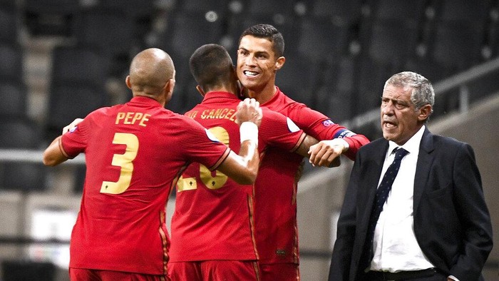 Portugals Christiano Ronaldo is congratulated on his 100th goal by Pepe, left, and Joao Cancelo, 2nd left,  and national team captain Fernando Santo, right, against Sweden during their UEFA Nations League Group stage soccer match at Friends Arena in Stockholm, Sweden, Tuesday Sept. 8, 2020. (Claudio Bresciani / TT via AP)
