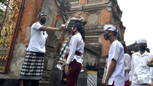 HARI RAYA GALUNGAN DI TENGAH PANDEMI COVID-19 Pecalang atau petugas pengamanan adat Bali memeriksa suhu tubuh umat Hindu yang akan bersembahyang saat Hari Raya Galungan di Pura Jagatnatha, Denpasar, Bali, Rabu (16/9/2020). Perayaan Hari Raya Galungan yang merupakan hari kemenangan kebenaran (Dharma) atas kejahatan (Adharma) tersebut diikuti umat Hindu di Pulau Dewata dengan tetap menerapkan protokol kesehatan secara ketat untuk mencegah penyebaran pandemi COVID-19. ANTARA FOTO/Fikri Yusuf/aww.