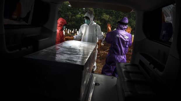 Petugas penggali makam jenazah COVID-19 bersiap menurunkan peti di komplek pemakaman Pondok Ranggon. ANTARA FOTO/Muhammad Adimaja