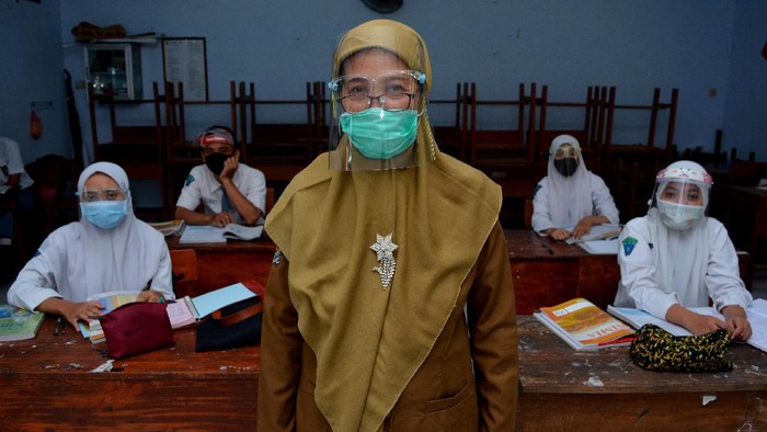 Seorang guru sekolah dasar mengajar pelajaran agama di rumah muridnya di Kelurahan Pesantren, Kota Kediri, Jawa Timur, Selasa (15/9/2020). Pembelajaran kelompok kecil di rumah siswa sekali dalam sebulan tersebut sebagai evaluasi penguasan materi pelajaran sekaligus upaya penyegaran agar siswa tidak bosan mengikuti pembelajaran jarak jauh.