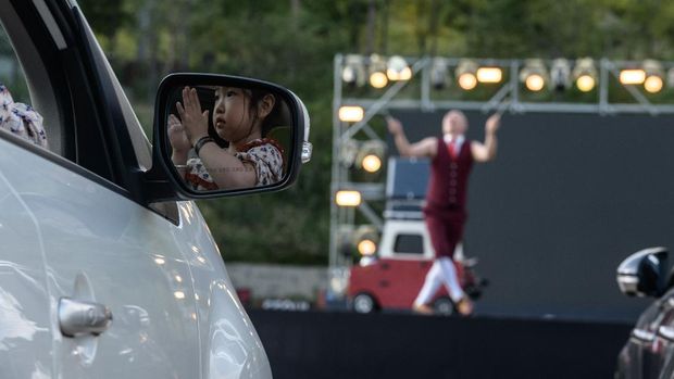 In a photo taken on September 19, 2020, a spectator watches from a car as a performer puts on a display at a drive-in circus performance in Seoul. - The annual circus -- usually held in May -- was pushed back twice this year because of the virus until organisers turned it into a drive-in event. (Photo by - / AFP)