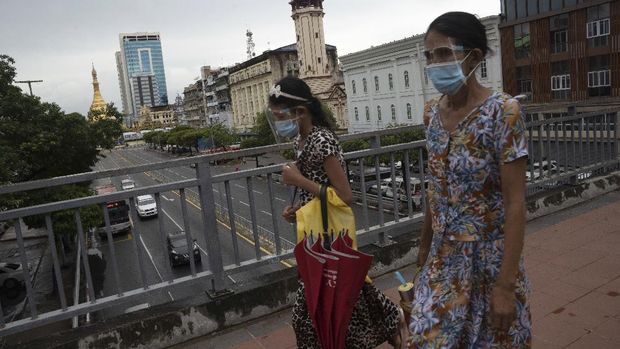 Pedestrians wearing face shields and masks walk at an overhead crossing at Sule Pagoda Road in Yangon, Myanmar,Monday, Sept. 21, 2020. Myanmar, faced with a rapidly rising number of coronavirus cases and deaths, has imposed the tightest restrictions so far to fight the spread of the disease in Yangon, the country's biggest city and main transportation hub. (AP Photo/Pyae Sone Win)
