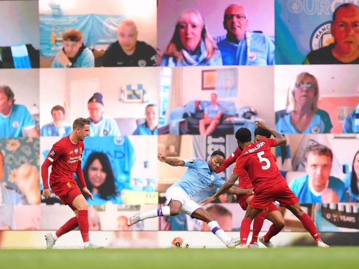 MANCHESTER, ENGLAND - JULY 02: Raheem Sterling of Manchester City is fouled in the penalty area by Joe Gomez of Liverpool as fans watch on the big screen during the Premier League match between Manchester City and Liverpool FC at Etihad Stadium on July 02, 2020 in Manchester, England. Football Stadiums around Europe remain empty due to the Coronavirus Pandemic as Government social distancing laws prohibit fans inside venues resulting in games being played behind closed doors. (Photo by Laurence Griffiths/Getty Images)