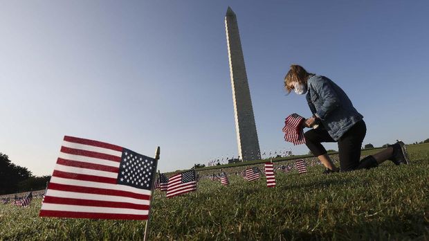 WASHINGTON, DC - SEPTEMBER 22: Carmen Wilke places flags at a COVID Memorial Project install of 20,000 American flags on the National Mall as the United States crosses the 200,000 lives lost in the COVID-19 pandemic September 22, 2020 in Washington, DC. The flags are displayed on the grounds of the Washington Monument facing the White House.   Win McNamee/Getty Images/AFP