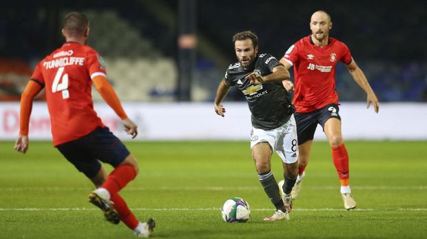 Manchester United's Juan Mata, center, is challenged by Luton Town's Danny Hylton, right, and Luton Town's Ryan Tunnicliffe during the English League Cup 3rd round soccer match between Luton Town and Manchester United, Tuesday, Sept. 22, 2020, at Kenilworth Road in Luton, England. (Cath Ivill/Pool via AP)