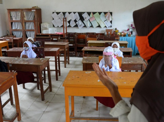 Guru mengajar anak berdoa pada hari pertama proses belajar mengajar di Sekolah Dasar Negeri Garot, Desa Ketapang, Kecamatan Darui Imarah, Kabapaten Aceh Besar, Aceh, Rabu (23/9/2020). Sebagian sekolah di daerah itu mulai melaksanakan aktivitas belajar mengajar tatap muka dengan membatasi jumlah murid dan tetap menerapkan protokol kesehatan guna mencegah penyebaran COVID-19. ANTARA FOTO/Ampelsa/aww.