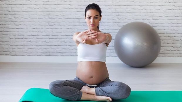 Shot of pretty young pregnant woman stretching after doing pilates exercises in the pre childbirth classroom.