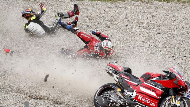 MotoGP rider Johann Zarco of France, left, and championship leader Andrea Dovizioso of Italy slide on the gravel after Zarco crashed into Dovizioso during the Catalunya Motorcycle Grand Prix at the Barcelona Catalunya racetrack in Montmelo, near Barcelona, Spain, Sunday, Sept. 27, 2020. (AP Photo/Joan Monfort)