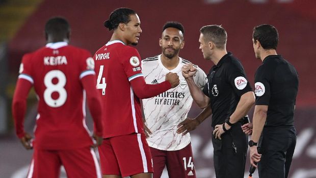 Liverpool captain Virgil van Dijk, second left, gestures to referee Craig Dawson, second right, as Arsenal's Pierre-Emerick Aubameyang watches the start of the English Premier League soccer match between Liverpool and Arsenal at Anfield in Liverpool, England, Monday, Sept. 28, 2020. (Laurence Griffiths/Pool via AP)
