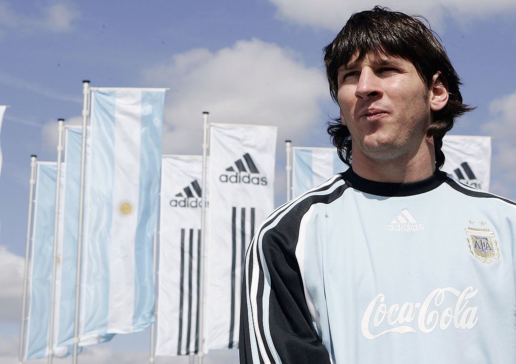 Herzogenaurach, Jerman - 4 Juni: Lionel Messi dari Argentina berdiri di depan bendera di Stadion Olahraga Dunia pada tanggal 4 Juni 2006 di Herzogenaurach, Jerman (Foto oleh Jan Pittmann / Getty Images untuk Adidas)